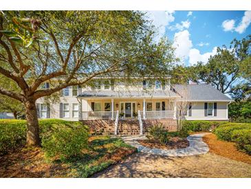 Charming two-story home with a welcoming front porch, mature trees, and landscaped front yard at 1511 Fairway Dr, Charleston, SC 29412