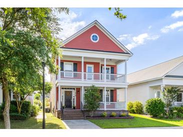 Charming two-story home with double porches, a red facade, and a professionally landscaped front yard at 218 Barberry St, Summerville, SC 29483