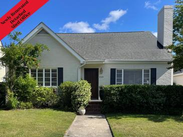Charming cottage-style home with a brick walkway, lush landscaping, and black shutters at 229 Gordon St, Charleston, SC 29403