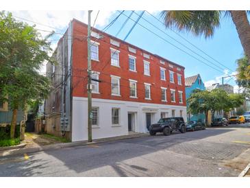 Three-story brick building with white trim and several windows, street view with parked cars at 35 Society St # D, Charleston, SC 29401