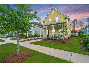 Charming yellow two-story home with a blue door, inviting porch, and freshly manicured lawn at 403 Ripple Park Dr, Summerville, SC 29486