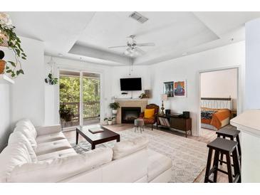 Bright living room with a white couch, fireplace, ceiling fan, and sliding glass doors to the balcony at 60 Fenwick # 936, Johns Island, SC 29455