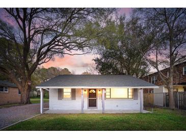 Charming single-story home with white brick, covered porch, and well-lit exterior at dusk at 706 White Oak Dr, Charleston, SC 29407