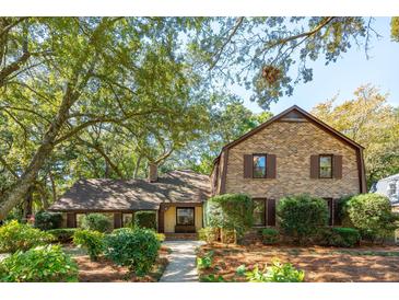 Charming brick home with mature trees and manicured landscaping creates a welcoming curb appeal at 810 Creekside Dr, Mount Pleasant, SC 29464