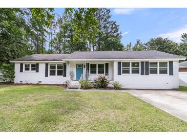 Charming one-story home with white brick exterior, well-manicured lawn, and a bright blue front door at 105 Evatt Dr, Goose Creek, SC 29445
