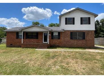 Two-story home featuring a classic brick exterior and a well-maintained lawn under a partly cloudy blue sky at 1110 Pickett St, Moncks Corner, SC 29461
