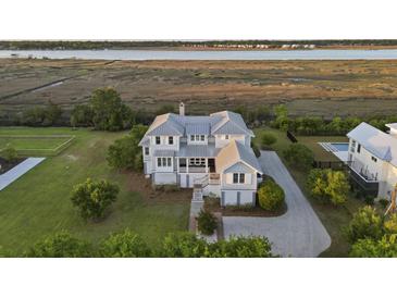 Stunning waterfront home with manicured lawn, mature trees, and a luxurious pool at 1518 Bower Ln, Johns Island, SC 29455