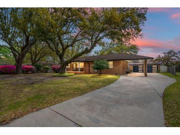 Charming brick home with mature trees, covered parking, and a spacious driveway at 1673 Mcclain St, Charleston, SC 29407