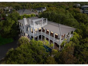Stunning aerial view of a luxurious two-story home featuring a private pool, lush landscaping, and spacious balconies at 3301 Palm Blvd, Isle of Palms, SC 29451