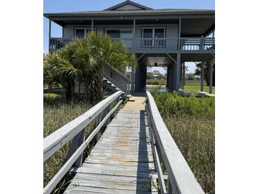 Charming elevated home with a wooden walkway and lush landscaping at 3807 Scott Creek Dr, Edisto Island, SC 29438