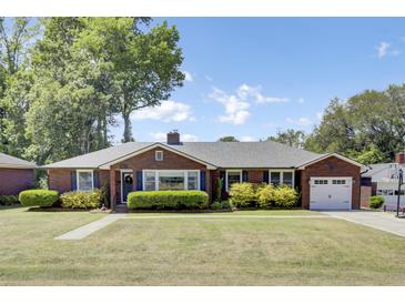 Charming brick home with well-maintained landscaping, a driveway, and an attached garage at 5029 Victoria Ave, North Charleston, SC 29405