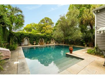 This in-ground pool features beautiful stonework, a fountain, lush landscaping, and privacy from the neighbors at 62 Society St, Charleston, SC 29401