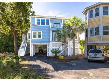 Charming coastal home with a light blue exterior, palm trees, and a covered parking area underneath at 73 Fairway Dunes Ln, Isle of Palms, SC 29451