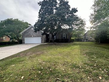 Charming single-story brick home with a lush front yard and mature trees, creating an inviting curb appeal at 104 Winston Way, Goose Creek, SC 29445