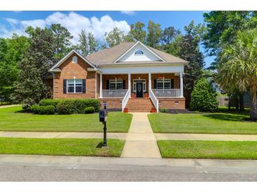 Charming brick home featuring a welcoming front porch, manicured lawn, and mature landscaping at 1069 Blockade Runner Pkwy, Summerville, SC 29485