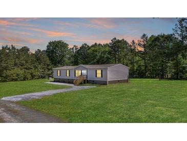 Charming single-story home with well-manicured lawn, gray siding, and surrounded by lush trees at sunset at 314 Hickory Nut Way, Cross, SC 29436