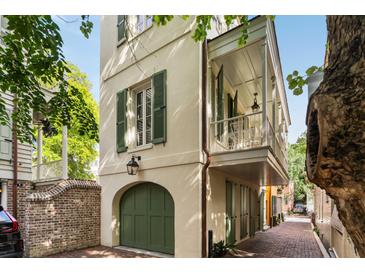Charming home exterior with green shutters, covered balcony, and brick paved walkway with arched garage at 4 Catfiddle St, Charleston, SC 29403