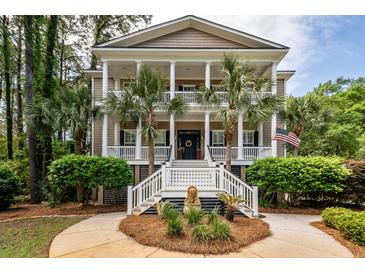 Charming two-story home with a columned front porch, manicured landscaping, and an American flag at 4991 Sound View Dr, Mount Pleasant, SC 29466