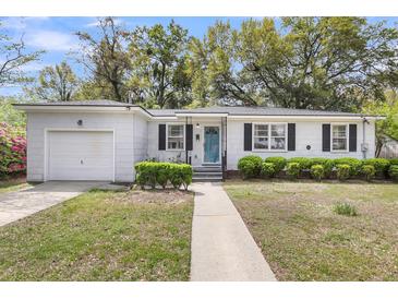 Charming single-story home featuring a blue door, manicured bushes, and an attached garage at 5075 Walker St, North Charleston, SC 29405