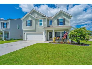 Charming two-story home featuring a well-manicured lawn, attached garage, and a welcoming front porch at 511 Nandina Dr, Goose Creek, SC 29445
