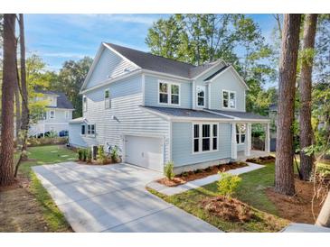 Charming two-story home features light blue siding, an attached garage, and a well-manicured front yard with mature trees at 5655 Captain Kidd Rd, Hollywood, SC 29449