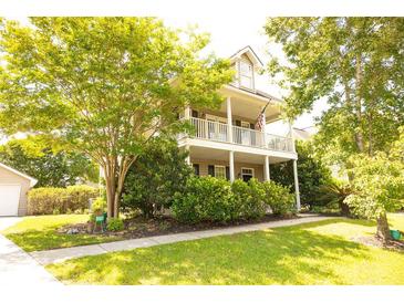 Charming two-story home featuring a welcoming front porch and lush landscaping, plus attached garage at 120 Full Moon Ct, Ladson, SC 29456