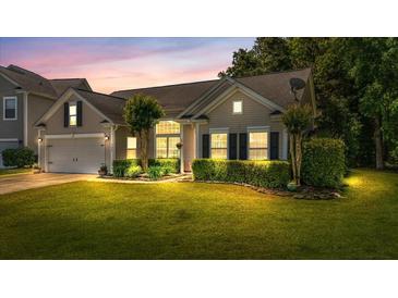 Charming single-Gathering home featuring a manicured lawn and lush landscaping at dusk at 124 Corral Cir, Summerville, SC 29485