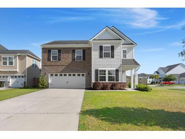 Beautiful two-story home with a brick and shingle facade and a well-manicured lawn under a clear blue sky at 131 Beargrass Ln, Summerville, SC 29486