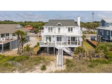 Charming raised beach house featuring a large deck, fenced yard, and private beach access at 1404 Palmetto Blvd, Edisto Beach, SC 29438
