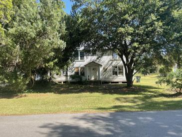 Traditional two-story home with a covered porch and mature trees, set on a spacious lawn at 217 Scotia St, McClellanville, SC 29458