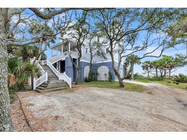 Charming beach house with a light-colored exterior, tall staircase, and lovely mature trees at 67 Lost Village Trl # 4, Edisto Island, SC 29438
