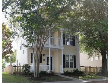 Charming two-story home with a welcoming front porch and balcony, complemented by lush trees and a picket fence at 86 Cross Timbers Dr, Summerville, SC 29485