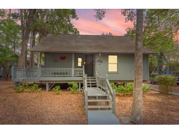 Charming coastal home with elevated porch and walkway surrounded by lush landscaping and trees at 208 Sea Cloud Cir, Edisto Island, SC 29438