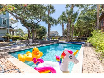 Refreshing backyard pool with fun inflatables, surrounded by a brick patio and lush greenery at 220 E Arctic Ave, Folly Beach, SC 29439