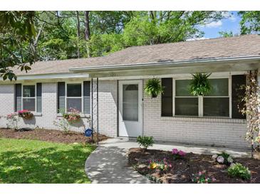 Charming brick home featuring a welcoming front door, manicured lawn and flower beds at 323 Millcreek Dr, Charleston, SC 29407