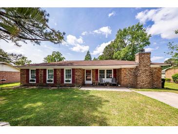 Charming brick home features a well-manicured lawn, red shutters, and inviting front porch at 104 Clover St, Summerville, SC 29483