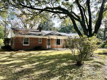 Charming brick home with a well-manicured lawn and mature trees creating a peaceful setting at 922 Dill Ave, Charleston, SC 29412