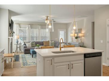 Bright kitchen boasts white cabinets, quartz countertops, and stainless steel appliances, flowing into the living area at 127 Surfbird Rd, Summerville, SC 29486