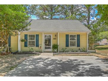 Charming one-story home featuring yellow siding, blue shutters, and a well-manicured lawn with mature trees at 1507 Blaze Ln, Charleston, SC 29412