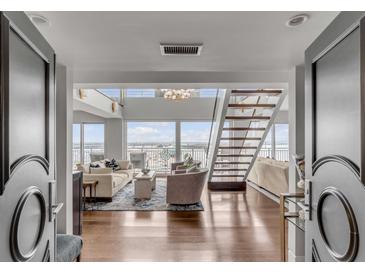 Bright, open-concept living room with hardwood floors, staircase, and water views at 330 Concord St # 18F, Charleston, SC 29401