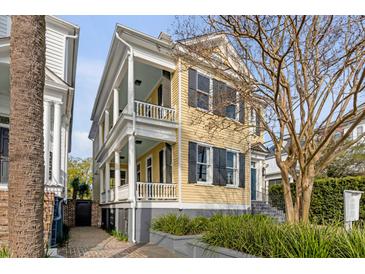 Charming two-story home with yellow siding, black shutters, and a double porch at 49 Ashley Ave, Charleston, SC 29401