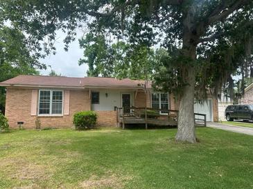 Charming single-story brick home featuring a well-maintained lawn, mature trees, and a convenient ramp at 104 Belmont Ct, Ladson, SC 29456