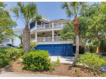 Charming coastal home featuring double balconies, a blue garage, and tropical landscaping at 3009 Palm Blvd, Isle of Palms, SC 29451