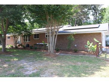 Charming brick home featuring solar panels, a well-maintained lawn, and mature trees for a serene and eco-friendly setting at 2404 Menola Ave, Charleston, SC 29414