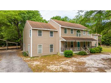 Charming two-story home featuring a covered front porch and lush surroundings at 312 Piney Grove Rd, Cross, SC 29436