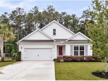 Charming one-story home featuring a well-manicured lawn, white exterior, and a bright pink front door at 512 Pontoon Rd, Huger, SC 29450