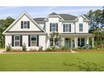 Charming two-story white farmhouse-style home with well-manicured lawn and landscaping at 1411 Homecoming Blvd, Ravenel, SC 29470