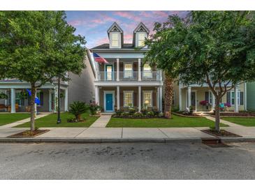 Charming two-story home featuring a welcoming front porch, colorful flower beds, and an American flag waving proudly at 422 Verbena Ave, Summerville, SC 29483