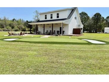 Expansive backyard featuring a putting green, fire pit, and lounge chairs for outdoor enjoyment and recreation at 795 Shagule Rd, Edisto Island, SC 29438