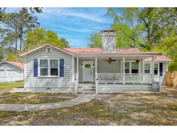 Charming home with a red metal roof, white siding, and a cozy front porch with flower baskets at 9666 Jamison Rd, Ladson, SC 29456